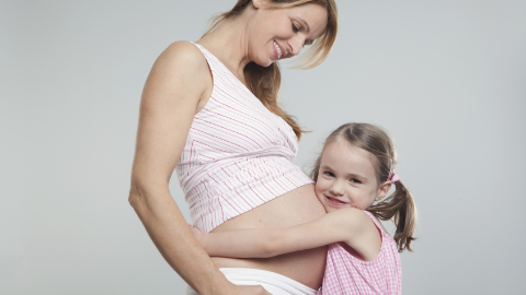 Ein Kind umarmt seine Mutter am Babybauch Ein Kind umarmt seine Mutter am Babybauch